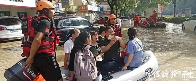 莫钢廷(拿手机男士身后穿救援服者)和队友用冲锋舟转移被洪水围困的群众